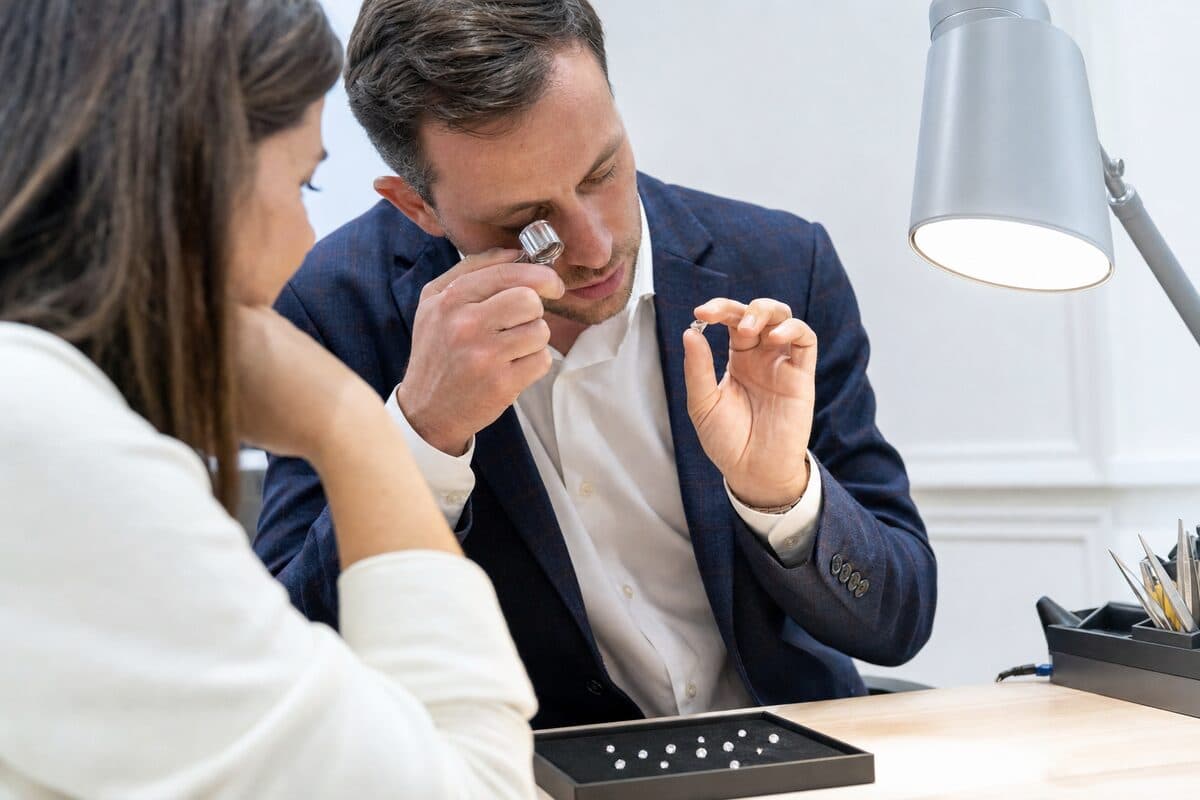 Diamond expert examining a loose stone with a loupe while explaining to the client